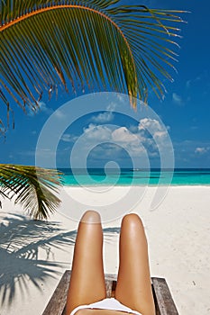 Woman at beach lying on chaise lounge