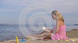 Woman on the beach reading a book.