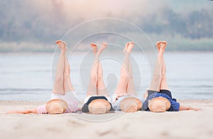 Woman on the beach relaxing concept, four women lying on sand tropical beach stretching up slender legs sea island in the