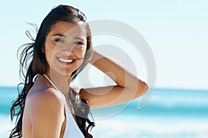 Woman, beach and smile in portrait with bikini in wind, holiday and face with pride in sunshine by ocean. Girl, person