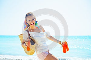 Woman with beach straw bag, flip flops and bottle of sunscreen