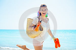 Woman with beach straw bag, flip flops and bottle of sunscreen