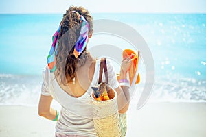 Woman with beach straw bag, orange flip flops and bottle of spf