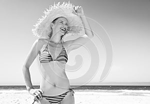 Woman in beach straw hat on seacoast looking into distance