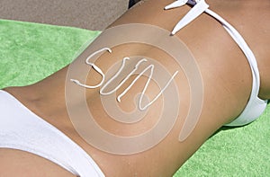 Woman beach sun written in sunlotion on back