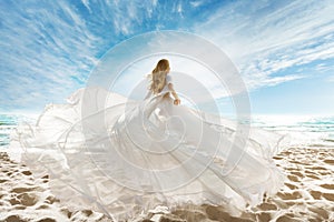 Woman on Beach in White Dress flying on Wind. Summer Vacation. Beach Sand Sea Sunshine Sky