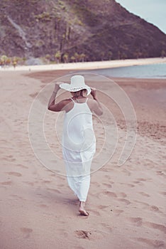 Woman on beach in white dress and hat