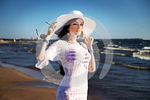 Woman on the beach in white hat and lace tunic. Summer