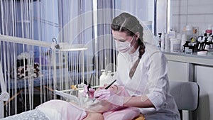 Woman beautician applies a mask to the face of a young woman with a brush.