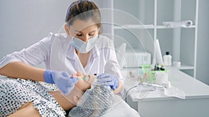 Woman beautician doing degreasing eyebrows using microbrush or cotton swab or tampon