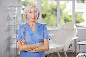 Woman beautician wearing blue overall posing in clinic of esthetic medicine photo