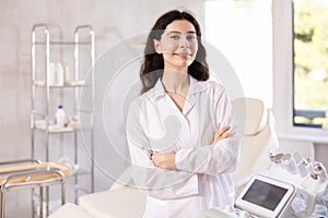 Woman beautician wearing overall posing in clinic of esthetic medicine