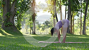 woman with beautiful athletic body and braided muscles stretching, raising her arms as she warms up in the park before
