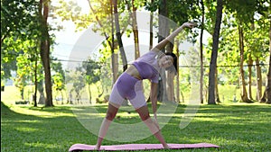 woman with beautiful athletic body and braided muscles stretching, raising her arms as she warms up in the park before