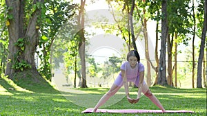 woman with beautiful athletic body and braided muscles stretching, raising her arms as she warms up in the park before