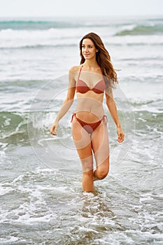 Woman with beautiful body enjoying her bath on the beach