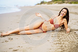 Woman with beautiful body laughing on a tropical beach wearing bikini