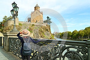 Woman on the beautiful bridge leading to Metekhi church on the cliff by Mtkvari river, Tbilisi, Georgia