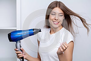 A woman with beautiful hair uses a hair dryer in the bathroom