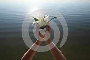 Woman with beautiful lily flower near river, closeup. Nature healing power