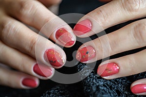 Woman with beautiful manicured red fingernails gracefully crossing her hands to display them to the viewer on a gray