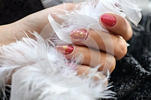 Woman with beautiful manicured red fingernails gracefully crossing her hands to display them to the viewer on a white