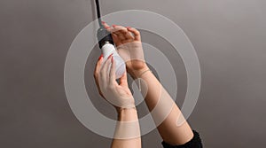 a woman with beautiful nails screws in an LED lamp