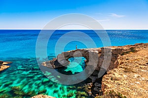 Woman on the beautiful natural rock arch near of Ayia Napa, Cavo Greco and Protaras on Cyprus island, Mediterranean Sea. Legendary photo