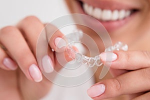 Woman beautiful smile holding a transparent mouth guard photo