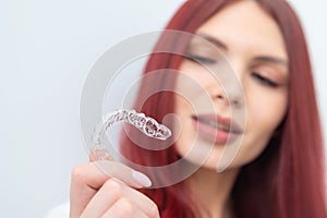 A woman with a beautiful smile holds aligners in her hand photo