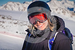 woman with a beautiful smile in a ski helmet. Portrait of a female skier in a safe ski helmet and goggles against the