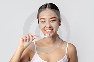 woman with beautiful smile with white teeth holding toothbrush with toothpaste on white background, smiles