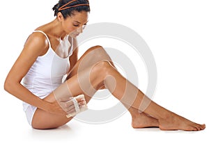 Woman, beauty and exfoliate legs on studio, white background and aesthetic wellness. Body care, exfoliation and cleaning