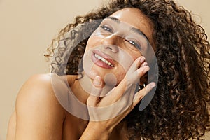 Woman beauty face close-up applying anti-aging moisturizer with fingers of her hand, skin health nails and hair, hair