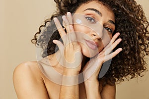 Woman beauty face close-up applying anti-aging moisturizer with fingers of her hand, skin health nails and hair, hair