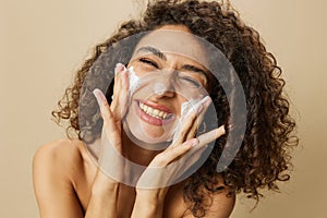 Woman beauty face close-up applying foam to wash and cleanse skin with fingers of her hand, nail and hair health, hair