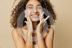 Woman beauty face close-up applying foam to wash and cleanse skin with fingers of her hand, nail and hair health, hair