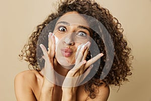 Woman beauty face close-up applying foam to wash and cleanse skin with fingers of her hand, nail and hair health, hair