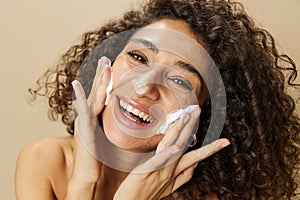 Woman beauty face close-up applying foam to wash and cleanse skin with fingers of her hand, nail and hair health, hair