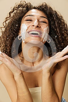Woman beauty face close-up applying foam to wash and cleanse skin with fingers of her hand, nail and hair health, hair