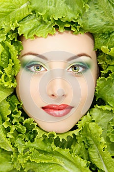 Woman beauty face with green fresh lettuce leaves