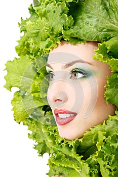 Woman beauty face with green fresh lettuce leaves