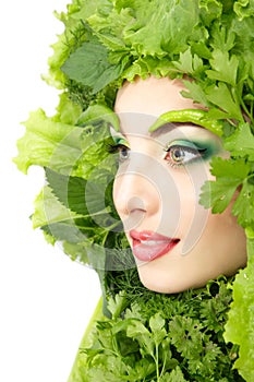 Woman beauty face with green fresh lettuce leaves