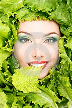 Woman beauty face with green fresh lettuce leaves