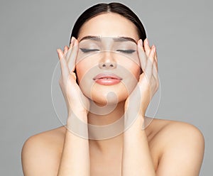 Woman Beauty Face. Women Skin Care and Make up. Model with closed Eyes enjoying Facial Massage. Facelift Cosmetology over Gray