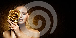 Woman Beauty Perfect glowing Skin Makeup. Fashion Model holding Golden Rose Flower over Face and covering Closed Eye. Artistic