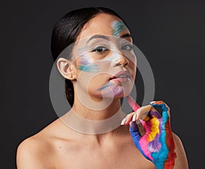 Woman, beauty and portrait with rainbow hand paint art on face in studio with glow. Creative skin and makeup on female