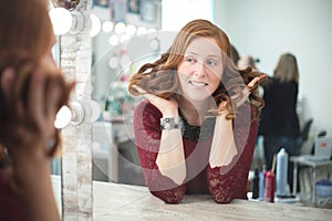 Woman in a beauty salon looks at her reflection in the mirror and checks hairstyle