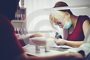 Woman at beauty salon receiving manicure treatment