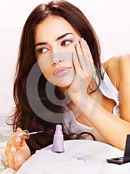 Woman in bed applying nail polish